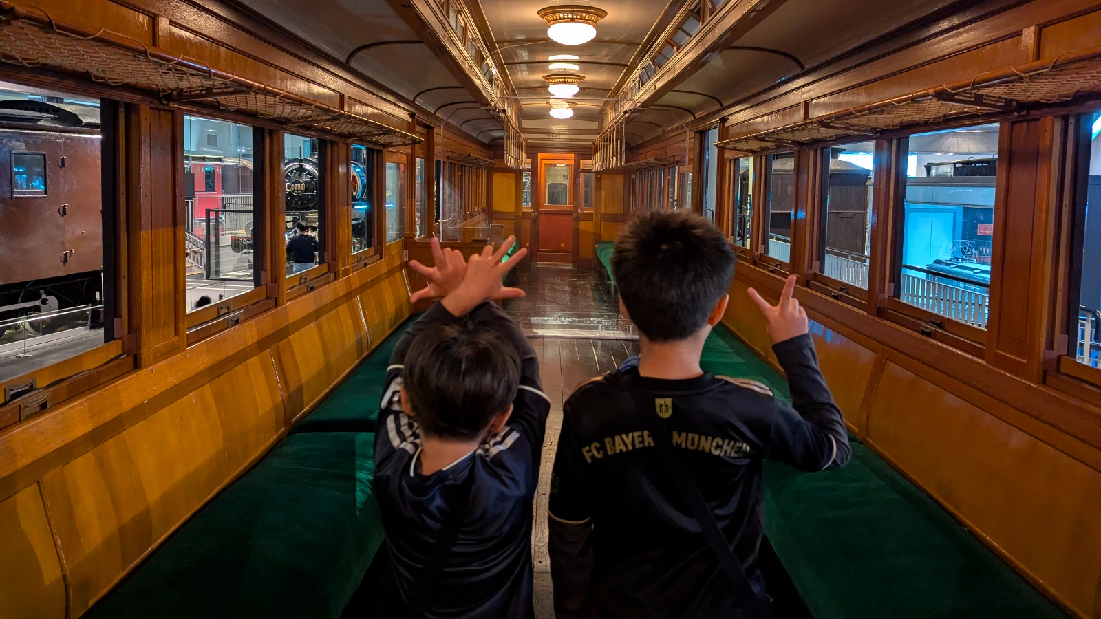 Children exploring the interior of a historic wooden train car at The Railway Museum, showing the craftsmanship and vintage design.