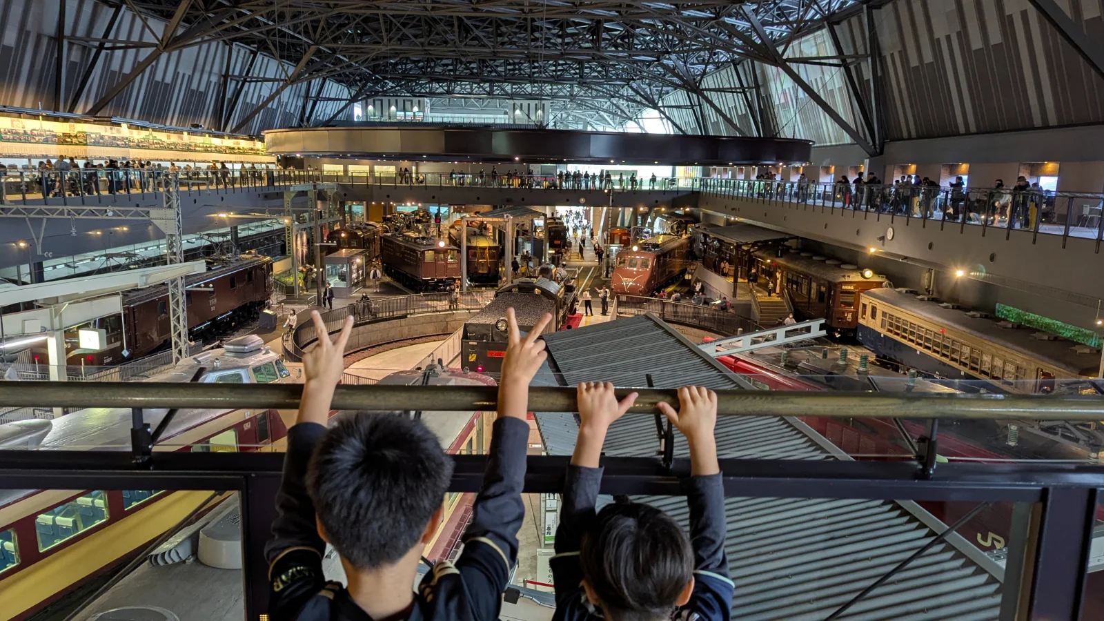 Children looking out over the turntable hall at The Railway Museum, with panoramic views of historic trains and the rotating platform.