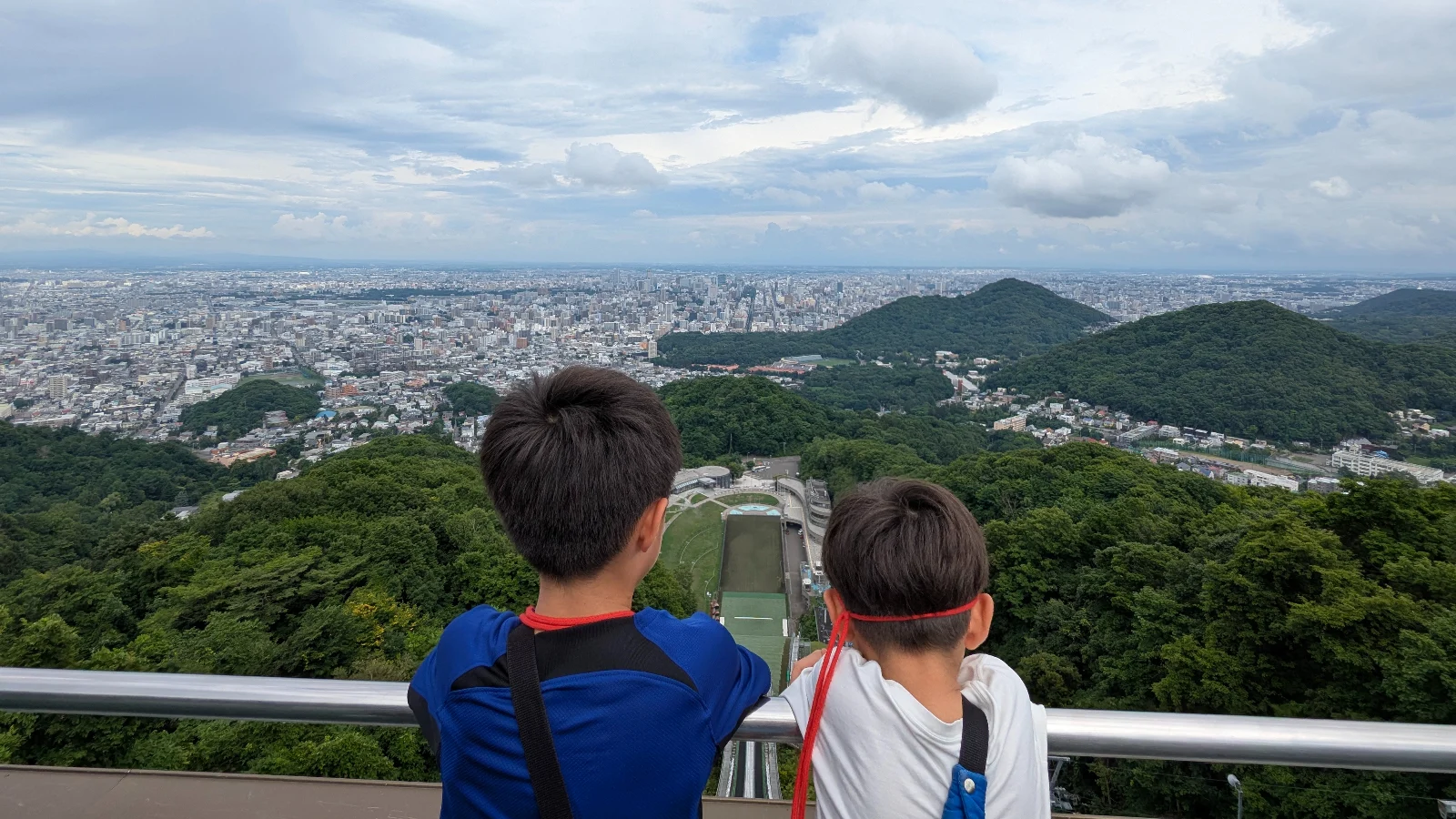 Two children looking over the Okurayama Ski Jump from the viewing deck at the Sapporo Olympic Museum, Japan family attraction.