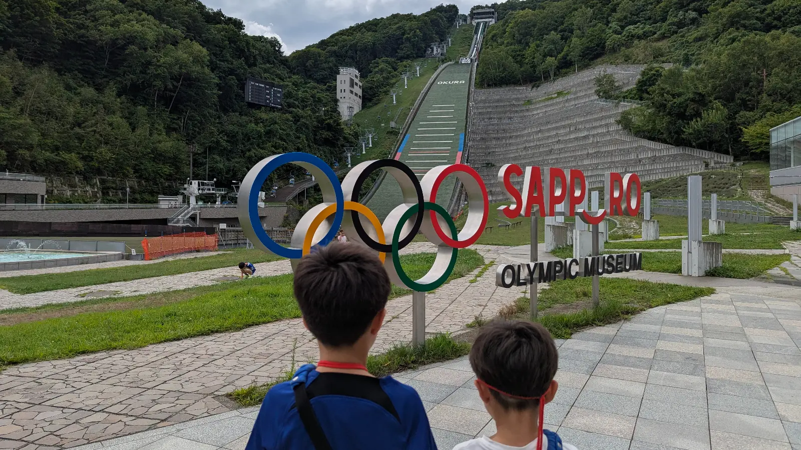Two children view the Olympic rings and ski jump tower at the Sapporo Olympic Museum in Okurayama, learning about Japan’s Winter Olympic history.