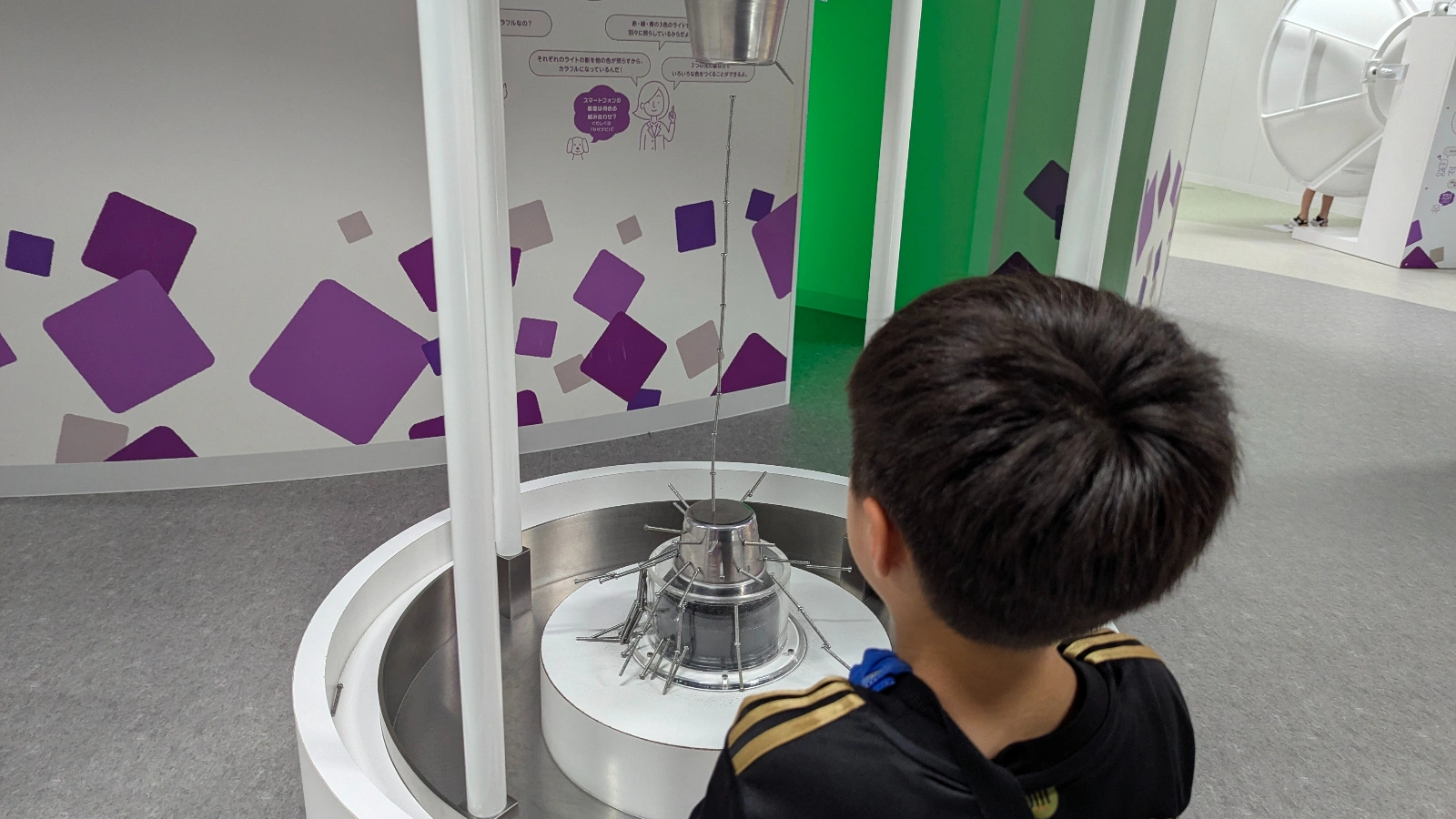 A child explores the magnetic force exhibit at Sapporo Science Center, stacking nails to see how magnet force connects through air.