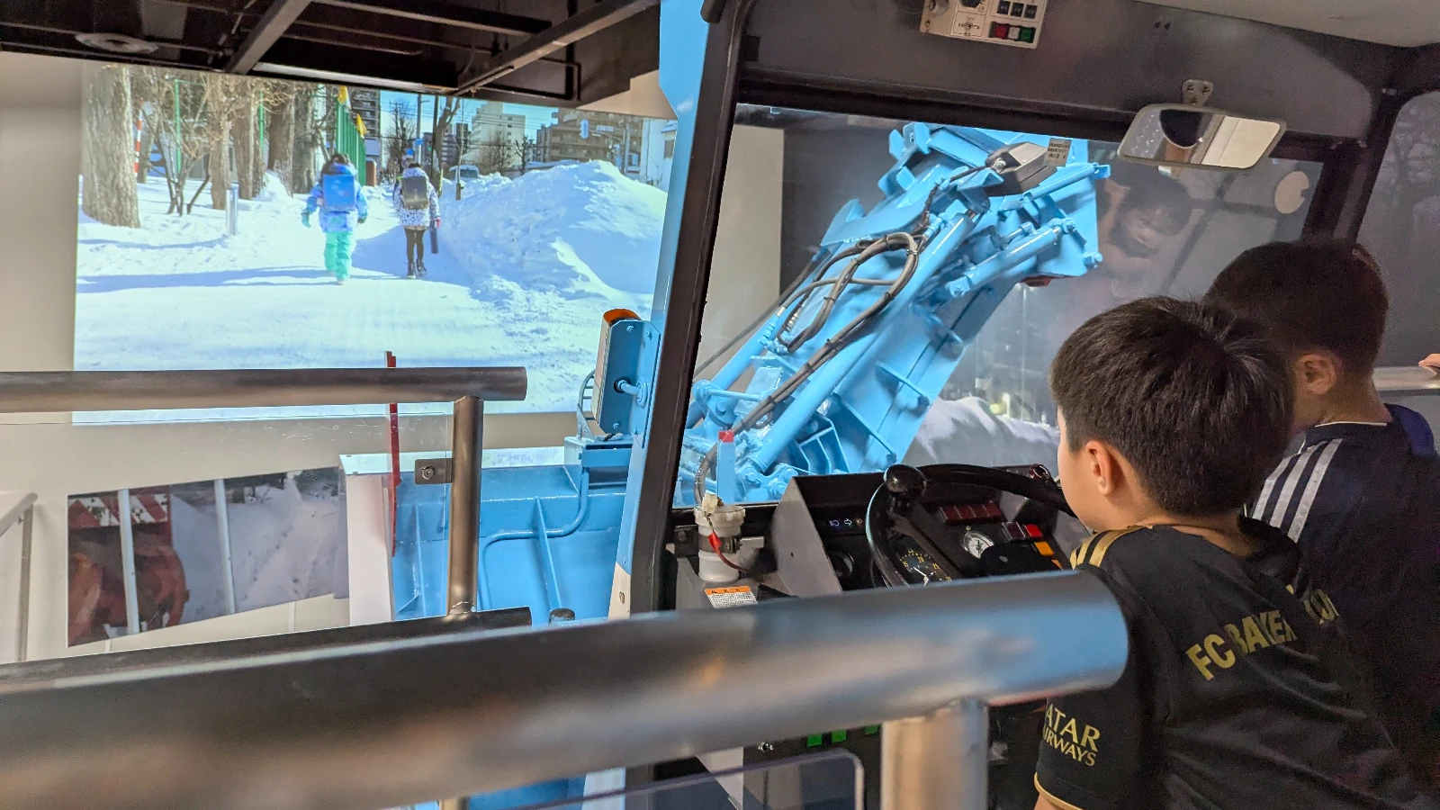 Children test the snowplow simulator at Sapporo Science Center, clearing snowy streets in an interactive winter science exhibit.