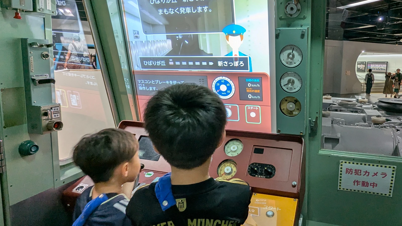 Two kids operate the subway simulator at Sapporo Science Center, learning how to drive a train through a realistic screen experience.