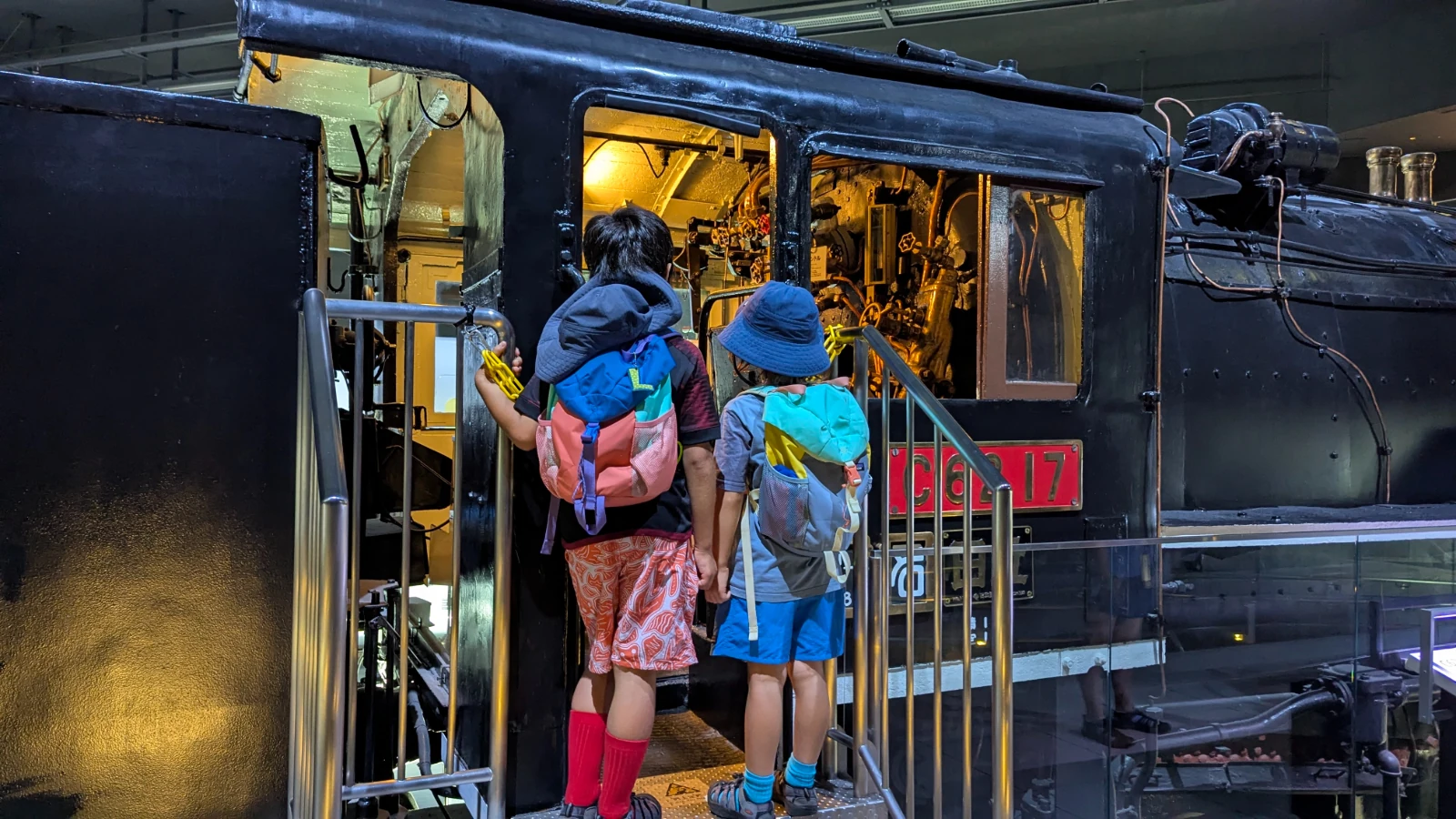 Luca and Nico peer into the cab of steam locomotive C62 17 at SCMaglev and Railway Park in Nagoya.