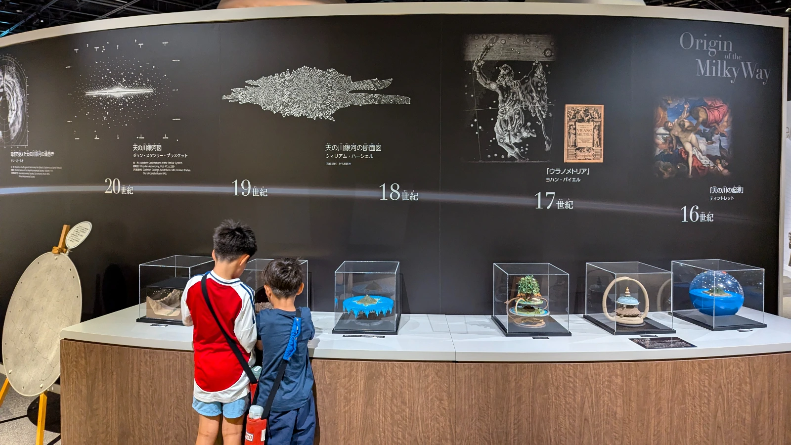 Children view the “Origin of the Milky Way” exhibit at the Sendai Astronomical Observatory, surrounded by detailed astronomy models and historical artwork.