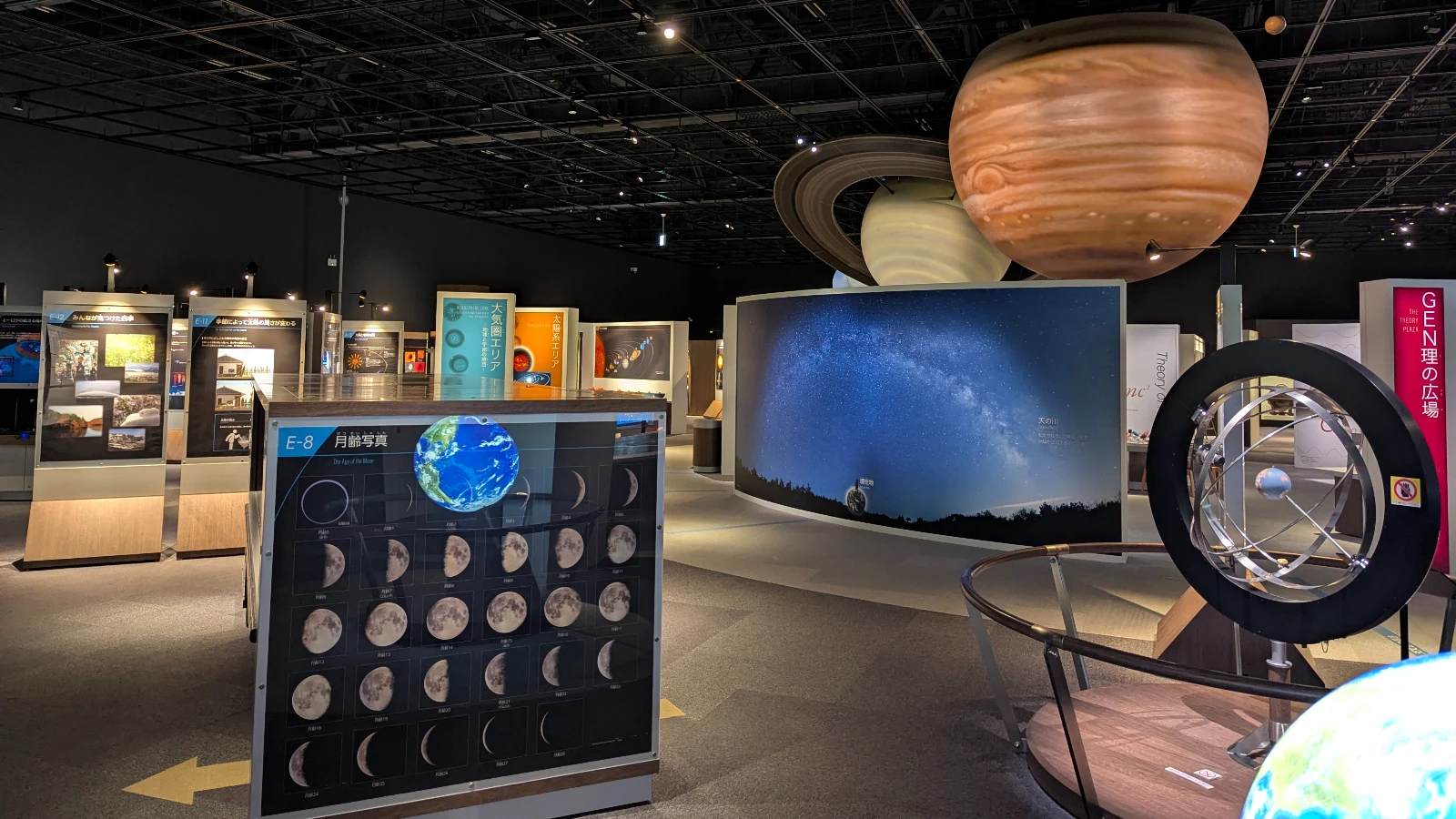 Interior view of the Sendai Astronomical Observatory with large planet models, moon phase panels, and space science exhibits for families and kids.
