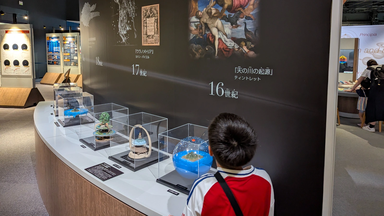A child explores a timeline of astronomy exhibits at the Sendai Astronomical Observatory in Japan, showcasing models from the 16th to 18th centuries.