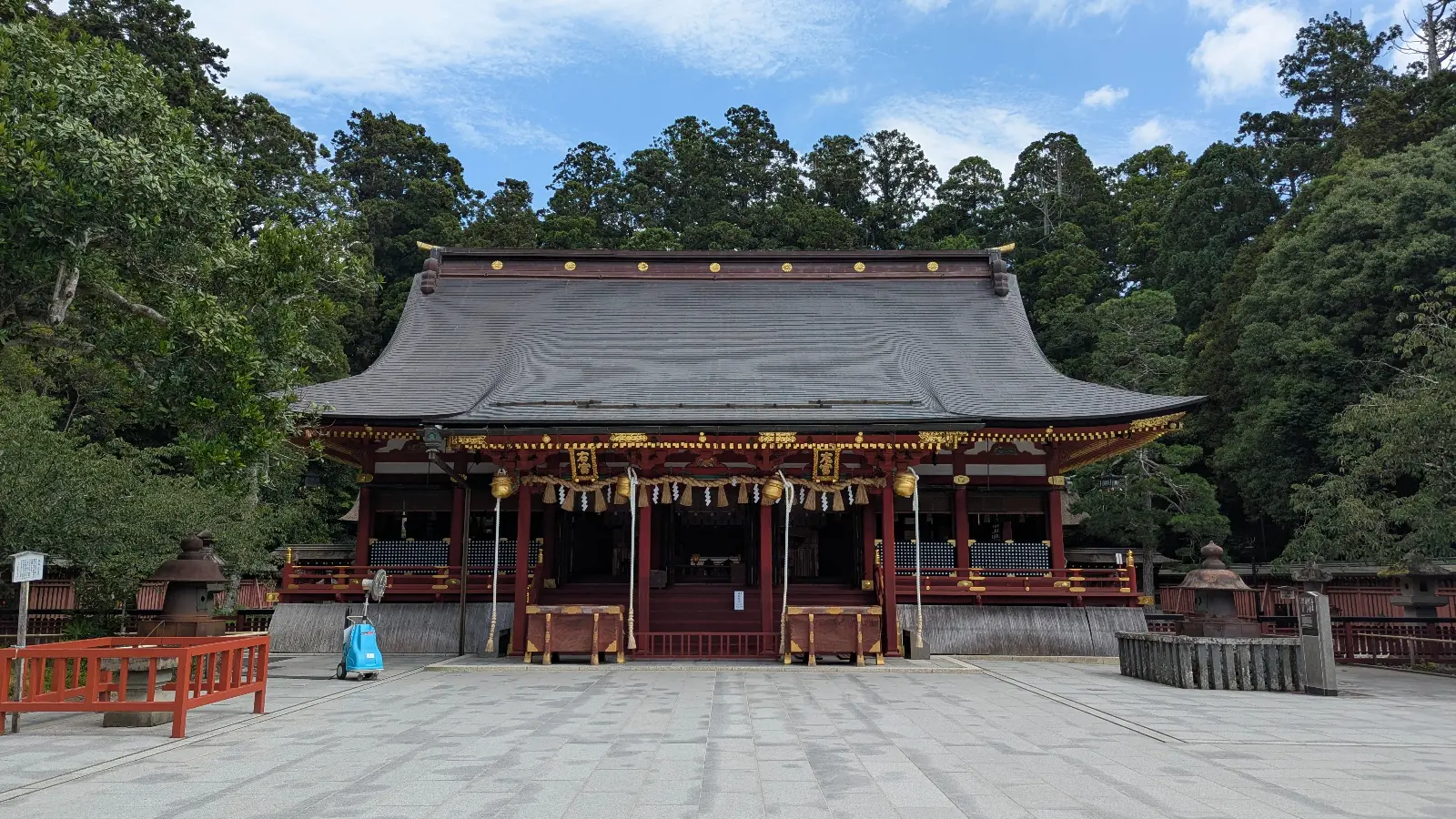 The main hall of Shiogama Shrine in Sendai, Miyagi, Japan surrounded by trees under a blue sky — a peaceful family travel photo.
