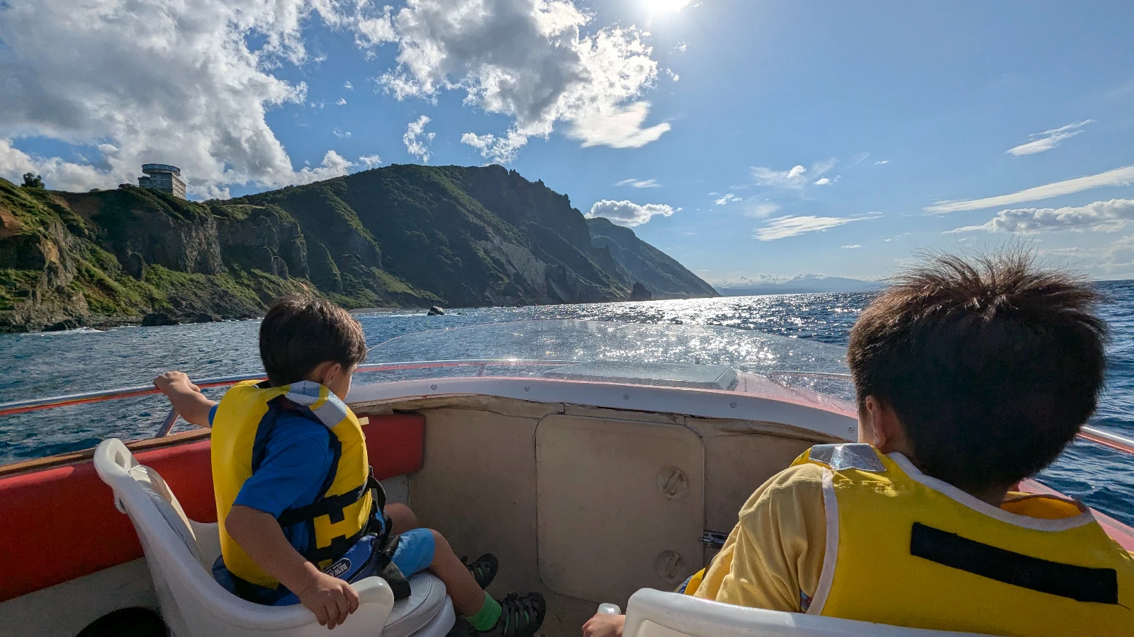 Children on a boat tour at Shiretoko Peninsula in Hokkaido, exploring dramatic coastal cliffs and ocean scenery.