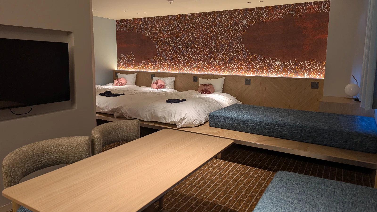 Japanese family hotel room with low futon-style bedding, tatami flooring, and seating area.