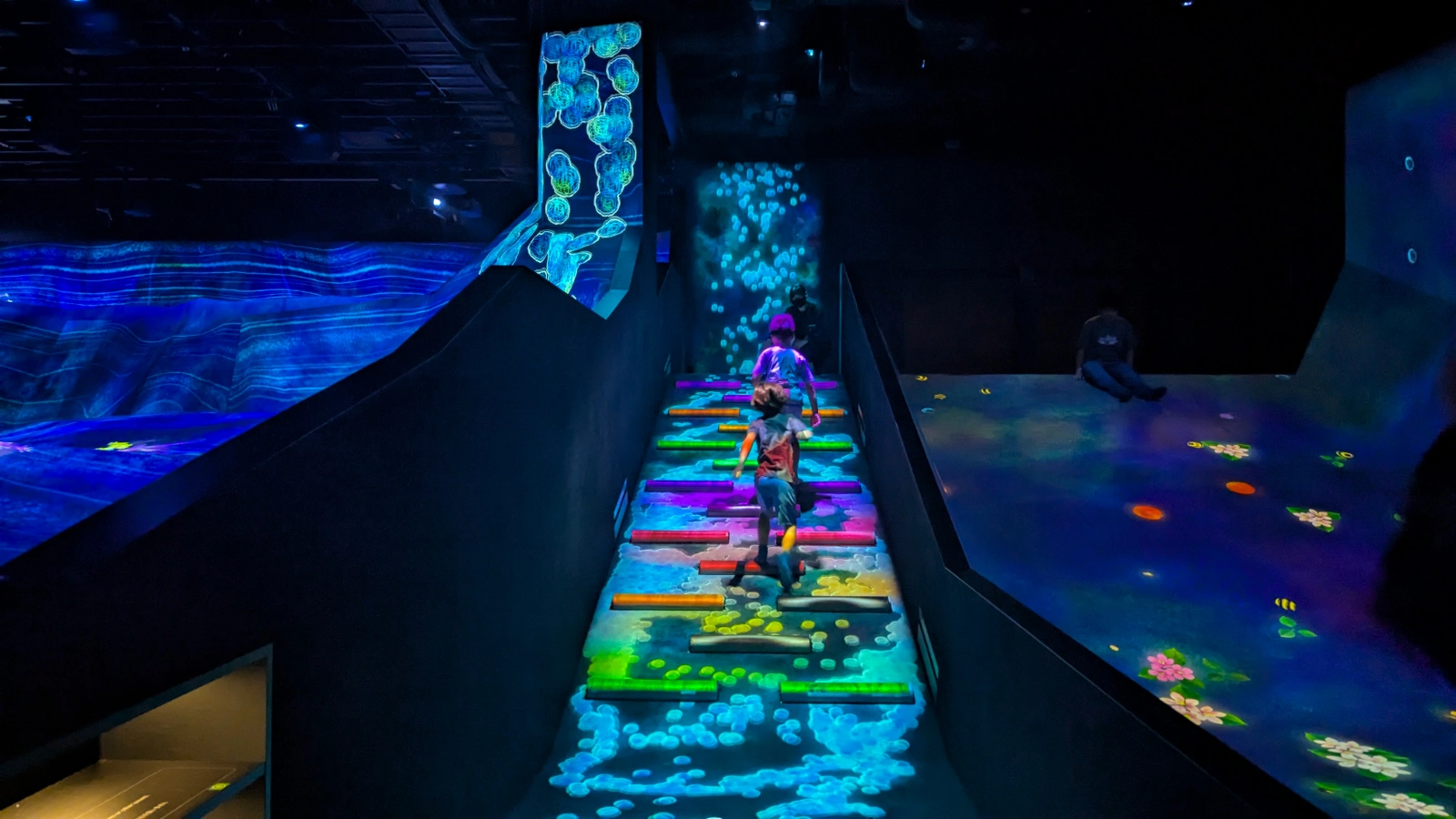 Luca and Nico crossing the glowing stepping-stone installation at teamLab Bio Vortex in Kyoto, Japan.