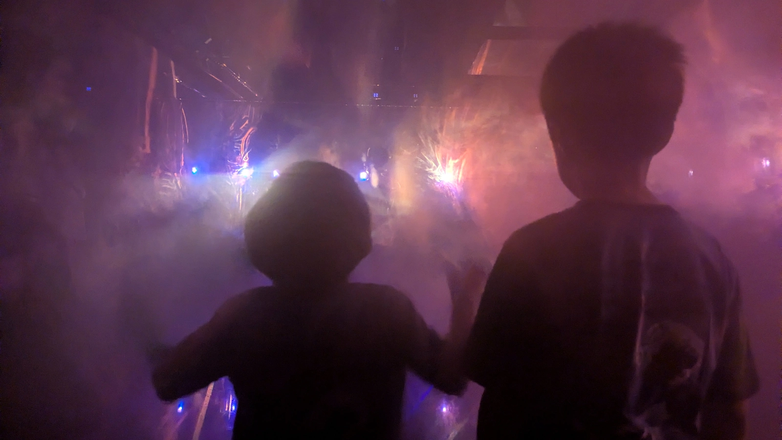 Children standing in a mist-filled digital art room at teamLab Borderless Tokyo, surrounded by purple haze and glowing lights.