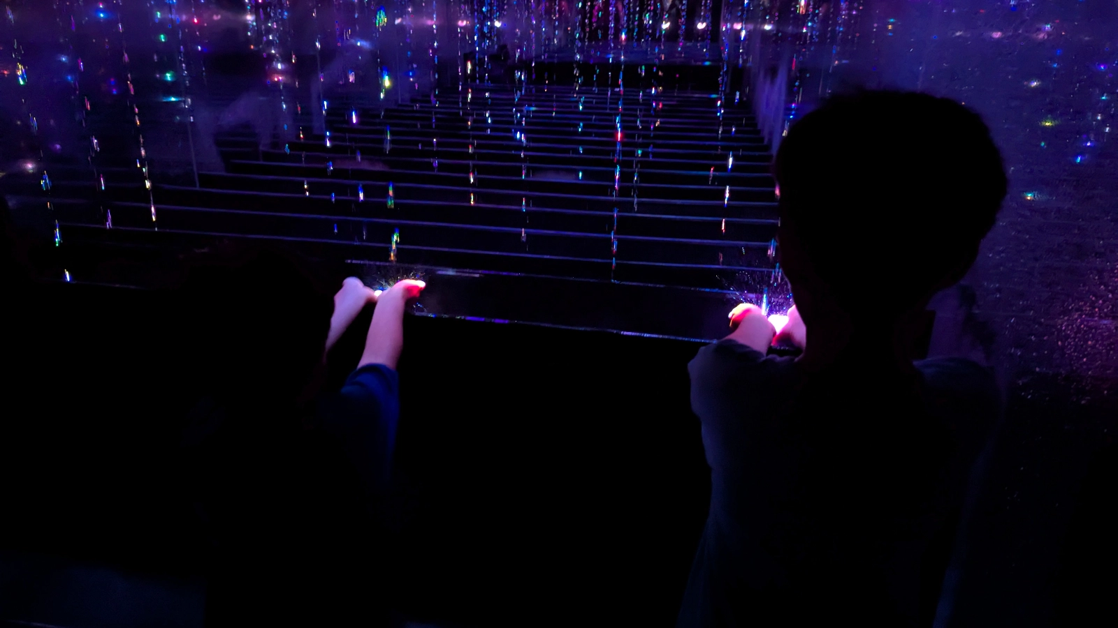 Children exploring the dazzling Mirror Room at teamLab Planets Tokyo, surrounded by glowing lights and reflections.