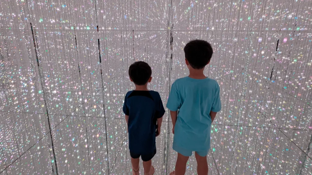 Luca & Nico stand barefoot in the Crystal Light Room at teamLab Planets Tokyo DMM (チームラボプラネッツ), surrounded by glowing LED lights.