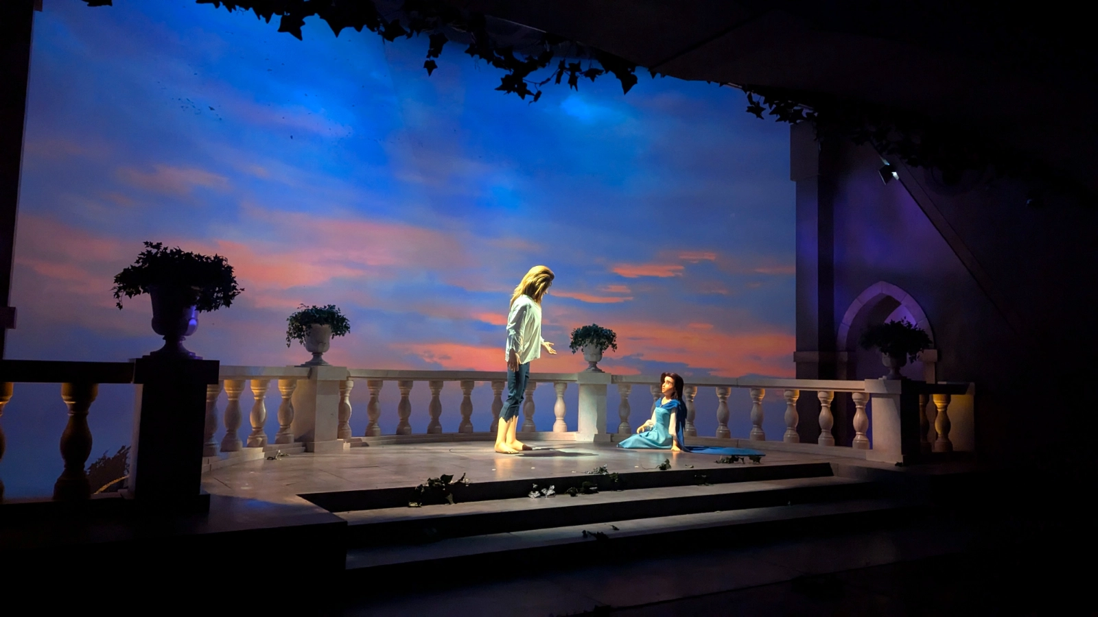 A scene inside Tokyo Disneyland’s Enchanted Tale of Beauty and the Beast ride, showing Belle and the Beast’s castle balcony glowing against a painted sunset sky.