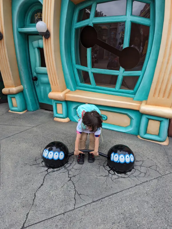Nico lifts a comical 10,000-pound cartoon weight in Toontown at Tokyo Disneyland, showcasing playful imagination during their Tokyo Disney family adventure.