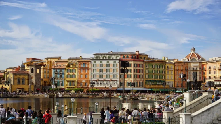 Colorful Mediterranean Harbor buildings at Tokyo DisneySea with families gathered by the waterfront.