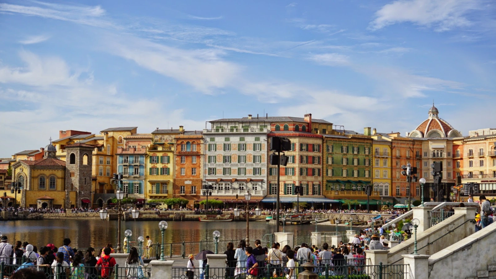 Colorful Mediterranean Harbor buildings at Tokyo DisneySea with families gathered by the waterfront.
