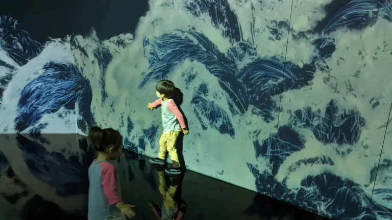 Luca & Nico interacting with digital wave art at teamLab Planets in Tokyo, a must-visit family attraction.