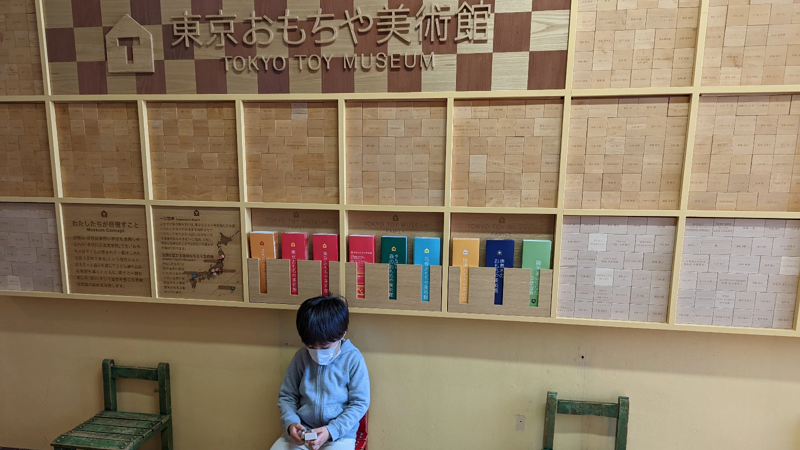 Child sitting under the Tokyo Toy Museum sign inside the museum building in Shinjuku Tokyo.