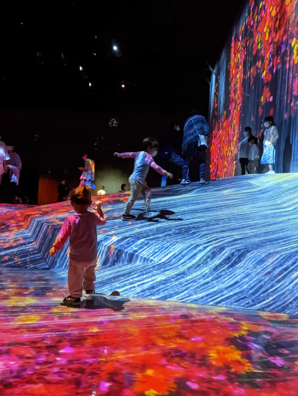 Luca & Nico play on a vibrant digital landscape at teamLab Planets in Tokyo, a sensory-rich art installation perfect for visiting Tokyo with kids.