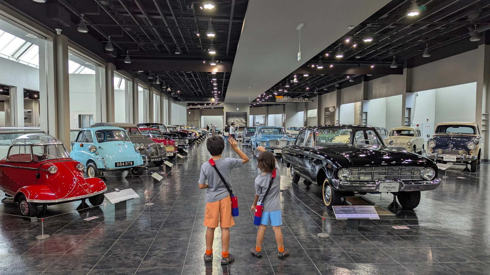 Luca and Nico wave down a long hall of 1950s and 1960s cars at the Toyota Automobile Museum in Nagakute, Aichi.