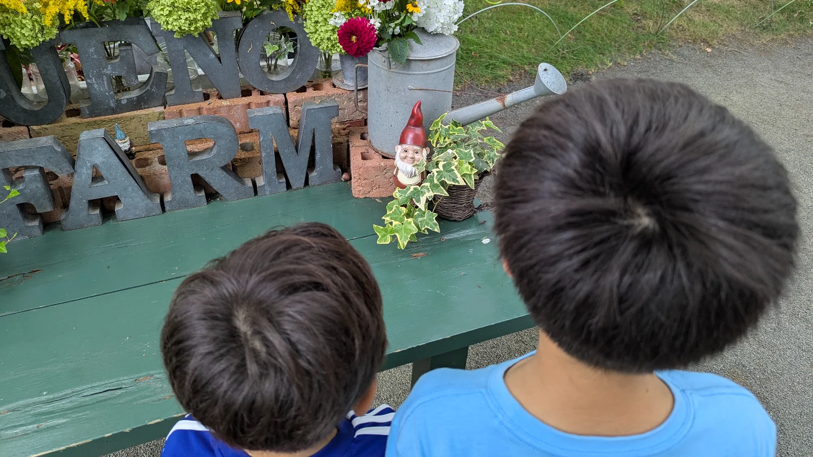 Two children look at a small garden gnome near the Ueno Farm sign during the gnome scavenger hunt in Asahikawa, Hokkaido.