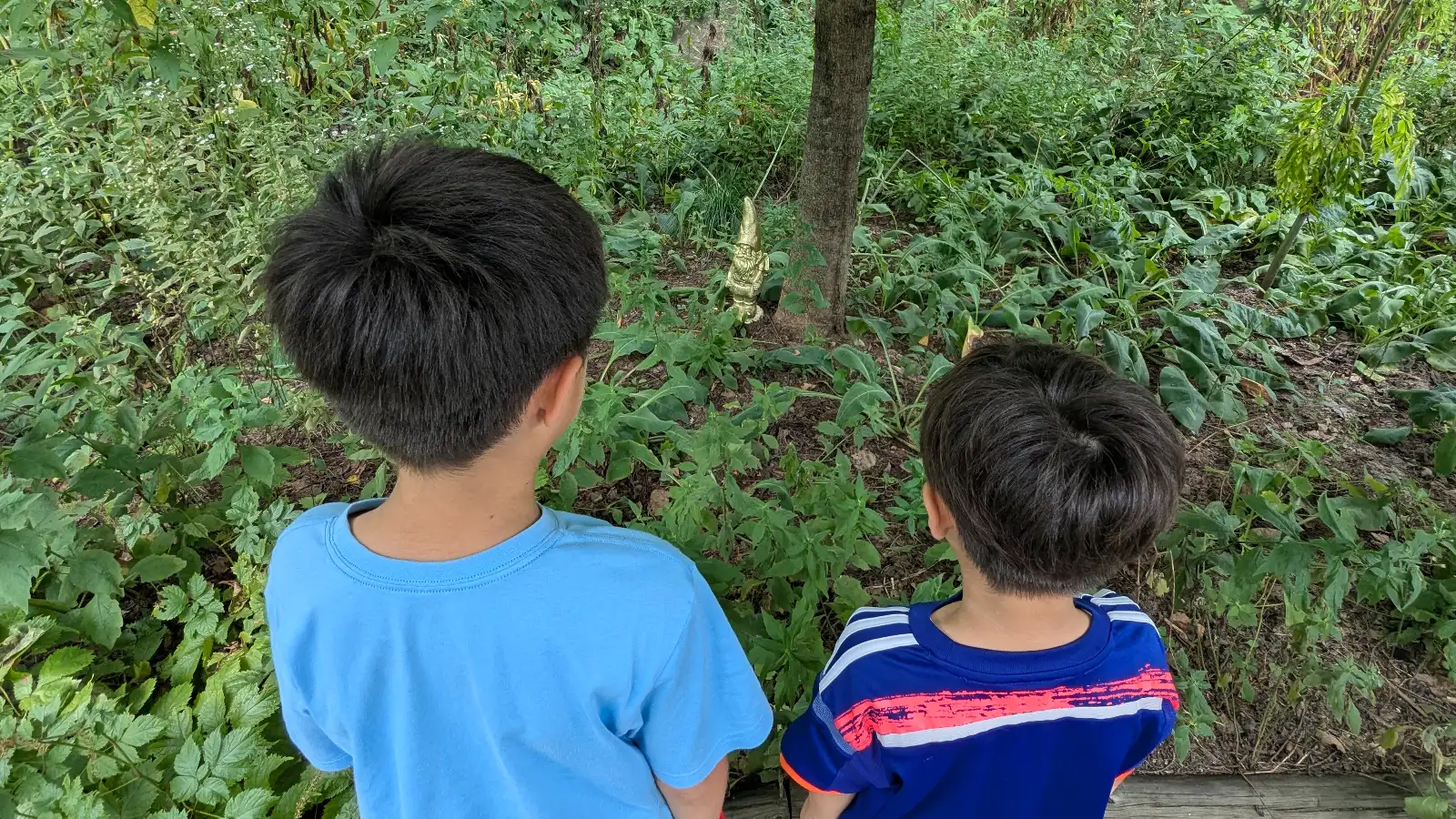 Two children search for hidden gnomes in the greenery at Ueno Farm, a whimsical garden attraction in Asahikawa, Hokkaido.