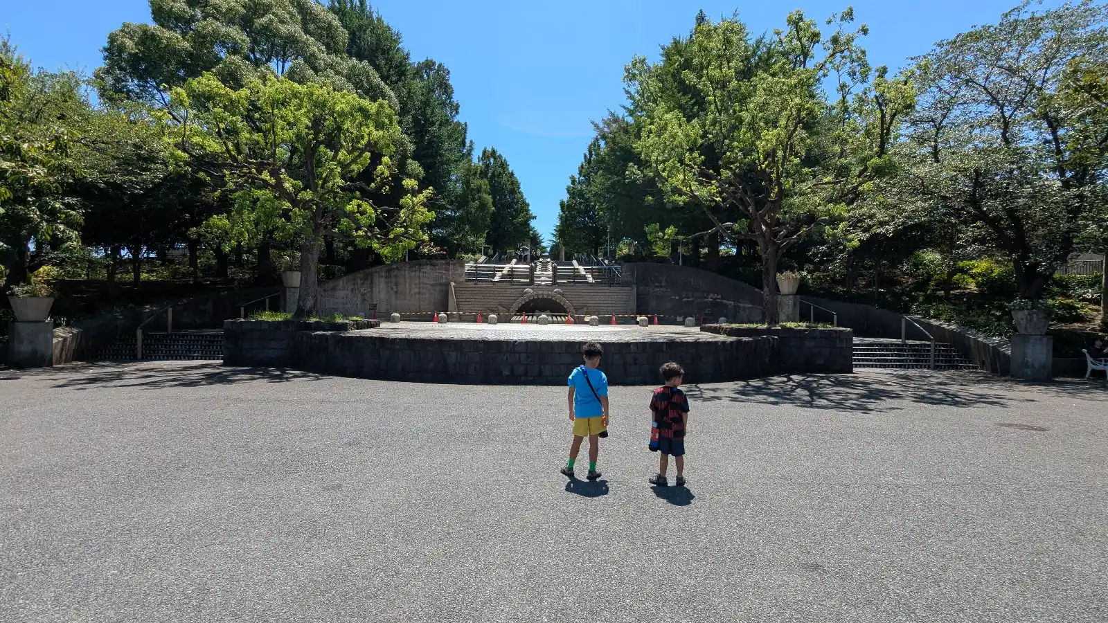 Luca & Nico standing in front of the dragon-shaped water fountain at Yamashita Park in Yokohama, known as the Mizu no Kaidan or “Water Stairs,” on a sunny day.