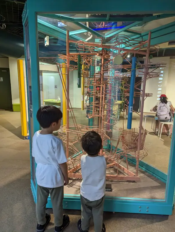 Luca & Nico observe a large marble run exhibit, enjoying an interactive science play zone in Yokohama.