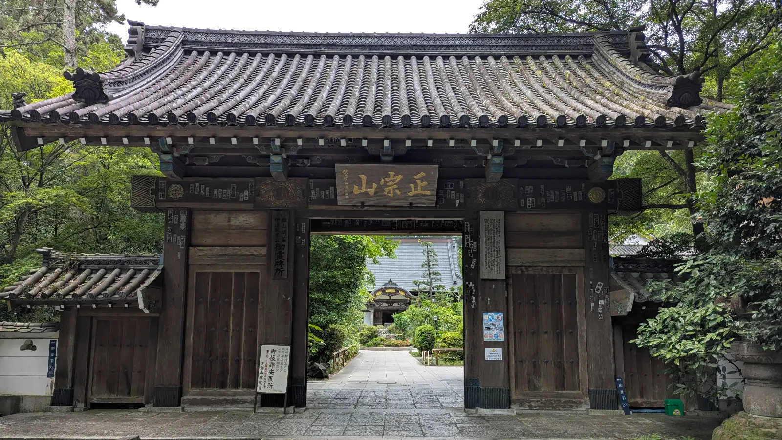 The wooden entrance gate to Zuihoden in Sendai, Japan, framed by green trees and traditional architecture that welcomes visitors to the mausoleum grounds.